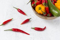Five red chili pods and bowl of various chili peppers — Stock Photo