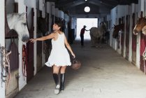 Smiling woman with riding helmet walking in stable — Stock Photo