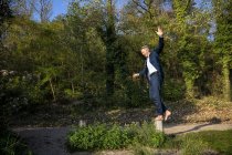 Geschäftsmann balanciert barfuß auf Stange in der Natur — Stockfoto