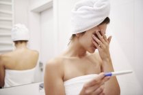 Молода жінка у ванній турбуючись про результат тесту на вагітність — стокове фото