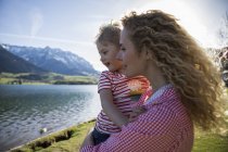 Austria, Tirol, Walchsee, madre feliz llevando hija en el lago - foto de stock