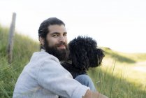 Junger Mann sitzt mit Hund im Gras — Stockfoto