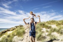 Netherlands, Zandvoort, father carrying daughter on shoulders in beach dunes — Stock Photo