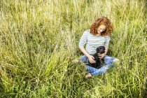 Young woman relaxing on meadow with dog — Stock Photo
