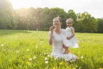 Mutter und Tochter im Sommer mit Pusteblume auf Wiese — Stockfoto