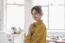 Ritratto di giovane donna che indossa una camicetta gialla in posa a casa — Foto stock