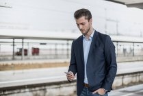 Geschäftsmann benutzt Handy am Bahnsteig — Stockfoto