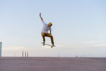 Young man doing a skateboard trick on a lane at dusk — Stock Photo