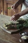 Young woman garnishing homemade chickpea and herb cake — Stock Photo