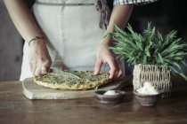 Junge Frau schneidet hausgemachte Kichererbsen und Kräuterkuchen — Stockfoto