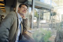 Homme d'affaires mature assis dans un café, regardant par la fenêtre — Photo de stock