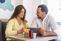 Young woman and man sharing tablet in a cafe — Stock Photo