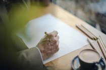 Homme d'affaires mature assis dans un café, dessin sur papier — Photo de stock