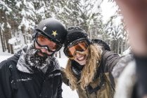 Selfie de pareja sonriente en ropa de esquí en el bosque de invierno - foto de stock