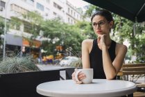 Joven empresaria sentada en la cafetería y bebiendo té - foto de stock