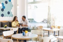 Mujer joven y hombre compartiendo tableta en un café - foto de stock