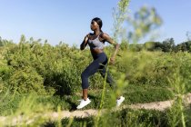 Young athlete jogging in green field — Stock Photo