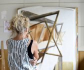 Pintora feminina em seu atelier, olhando para quadro de pintura — Fotografia de Stock
