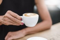 Close-up of senior woman holding a cup of cappuccino — Stock Photo