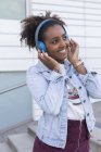 Smiling young woman listening music in blue headphones — Stock Photo