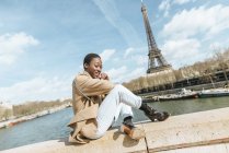 França, Paris, Mulher sentada na ponte sobre o rio Sena com Torre Eiffel no fundo — Fotografia de Stock