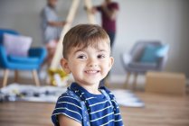 Portrait of smiling boy at home with parents in background — Stock Photo