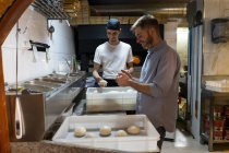 Due uomini con pasta cruda in scatole in cucina di una pizzeria — Foto stock