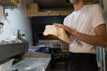 Primer plano del panadero de pizza preparando masa de pizza en la cocina - foto de stock