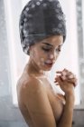 Сорочки молода жінка з рушником навколо голови позує у ванній — стокове фото