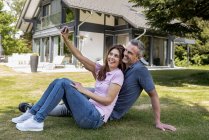 Coppia felice seduta nel giardino della loro casa a farsi un selfie — Foto stock