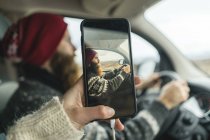 Islandia, mujer tomando fotos de su novio conduciendo furgoneta - foto de stock