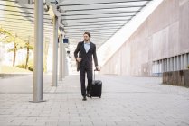 Uomo d'affari in movimento spingendo valigia rotolamento — Foto stock