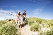 Holanda, Zandvoort, família feliz com a filha correndo em dunas de praia — Fotografia de Stock
