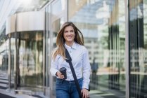 Giovane donna d'affari sorridente con borsa e caffè da portare via — Foto stock