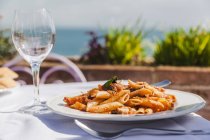 Italy, Atrani, plate of Penne Rigate with tomato sauce and tuna — Stock Photo