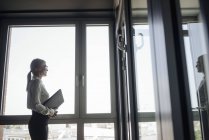Empresária no escritório olhando pela janela — Fotografia de Stock
