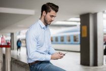 Geschäftsmann benutzt Handy am Bahnhof — Stockfoto
