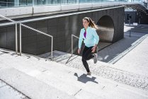 Jovem mulher correndo em escadas na cidade — Fotografia de Stock