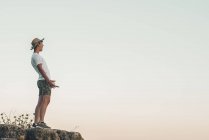 Молодой человек, стоящий на камне и кричащий от радости — стоковое фото