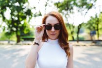 Portrait of redheaded woman wearing sunglasses in park — Stock Photo