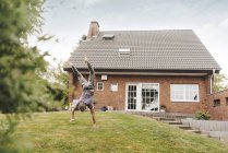 Hombre maduro haciendo handstand en jardín de casa - foto de stock