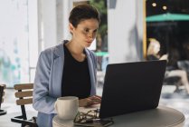 Young businesswoman sitting in coffee shop and using laptop — Stock Photo