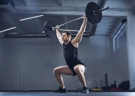 Людина робить штангою вправи в тренажерному залі під час підняття важких тренувань — стокове фото