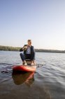 Empresário relaxante com bebida em paddleboard em um lago — Fotografia de Stock