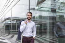 Retrato de jovem empresário sorridente na fachada de vidro — Fotografia de Stock