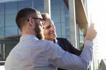 Два бизнесмена делят планшет на открытом воздухе — стоковое фото