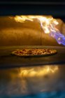 Піца в духовці з палаючим вогнем — стокове фото