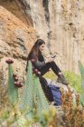 Espanha, Alquezar, jovem mulher sentada em uma rocha e usando smartphone — Fotografia de Stock