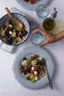 Donna che serve orecchiette mediterranee con pomodori, olive e mozzarella, bicchiere d'acqua — Foto stock