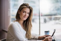 Ritratto di giovane donna d'affari sorridente in un caffè con tablet — Foto stock